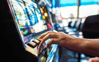 A Hand of a Gambler Playing Slots Inside of a Casino